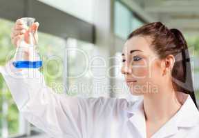 Cute science student looking at a blue liquid