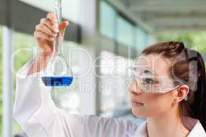 Young science student looking at a blue liquid