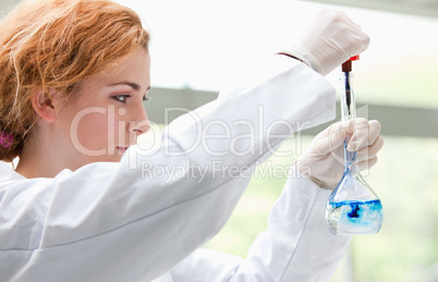 Science student putting blue drops in a liquid