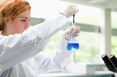 Cute science student putting blue drops in a liquid