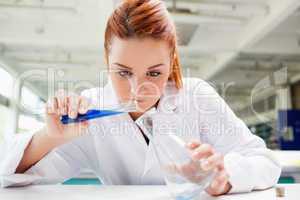 Beautiful scientist pouring liquid