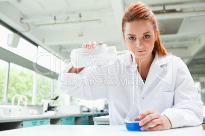 Red-haired scientist pouring liquid in a flask