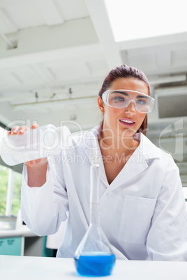 Portrait of a female science student pouring liquid with protect