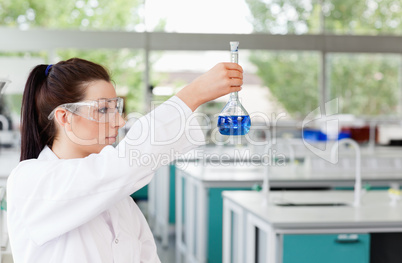 Brunette scientist looking at a flask