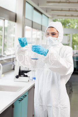 Portrait of a protected scientist pouring liquid in a Erlenmeyer