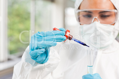 Protected scientist dropping a liquid in a test tube