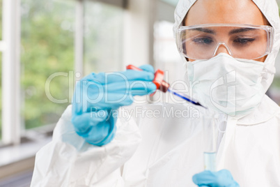 Protected science student dropping a liquid in a test tube
