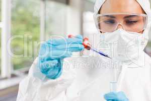Protected science student dropping a liquid in a test tube