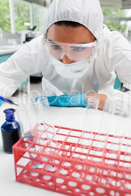 Portrait of a protected female scientist dropping blue liquid in