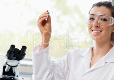 Smiling science student holding a microscope slide