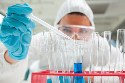 Close up of a protected scientist dropping liquid in a test tube