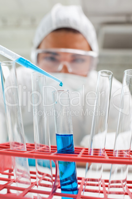 Portrait of a protected science student dropping blue liquid in