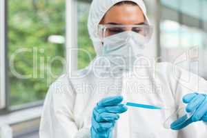 Protected female science student dropping blue liquid in a Petri