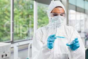 Protected science student dropping blue liquid in a Petri dish