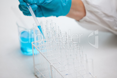 Protected hand dropping liquid in a test tube