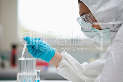 Close up of a protected female scientist dropping liquid in a te