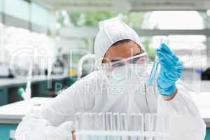 Protected female scientist looking at a test tube