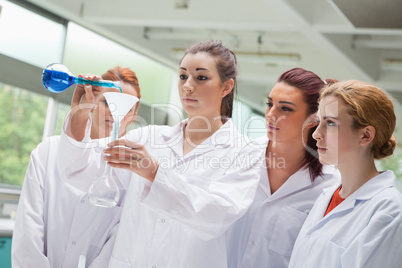 Female science students pouring liquid in a flask