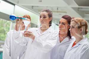 Female science students pouring liquid in a flask