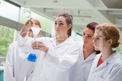 Cute science students pouring liquid in a flask