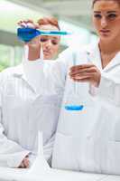 Portrait of scientists pouring liquid into a flask