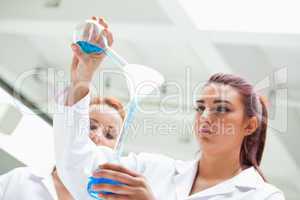 Scientist emptying a flask into another one
