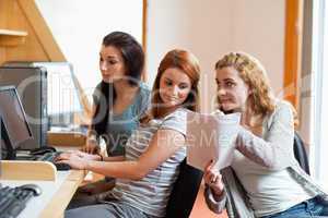 Cute student showing her notes to her classmate