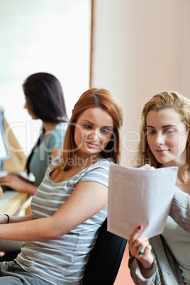 Portrait of a student showing her notes to her classmate