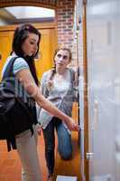 Portrait of student opening her locker while speaking with her f