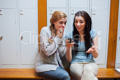 Surprised student showing a text message to her friend
