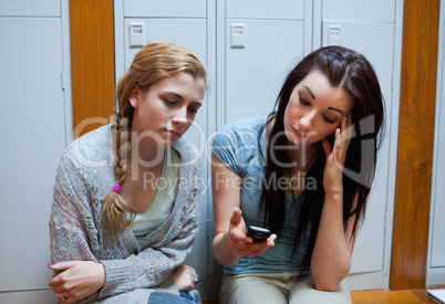 Sad student showing a text message to her friend
