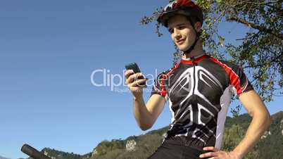 Young man with mobile telephone riding mountain bike