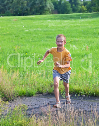 Small boy running on green meadow