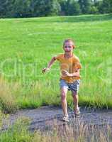 Small boy running on green meadow