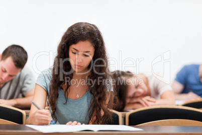 Students writing while their classmate is sleeping