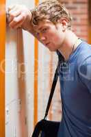Portrait of a lonely student leaning on a locker