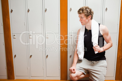 Handsome young sports student leaning on a locker