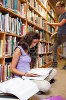 Portrait of a student reading a book while her classmate is choo