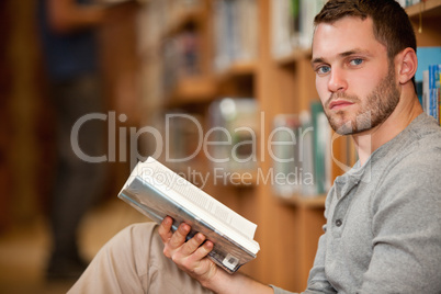 Serious male student holding a book