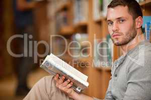 Serious male student holding a book