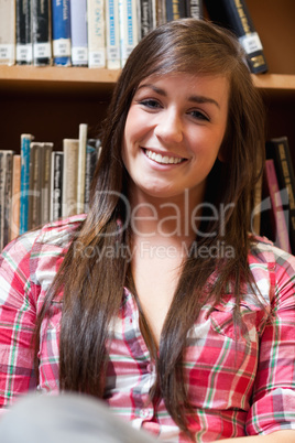 Portrait of a smiling student sitting against shelves