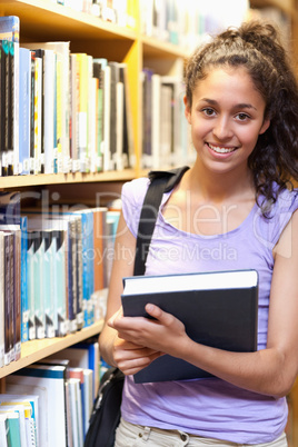 Portrait of a smiling female student posing with a book