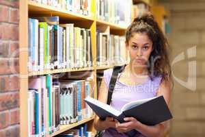 Serious female student holding a book