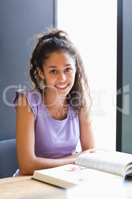 Portrait of a smiling student sitting with a book