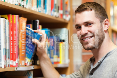 Smiling male student picking a book