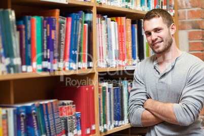 Smiling male student leaning on a shelf