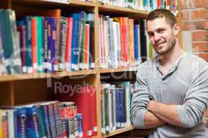 Smiling male student leaning on a shelf