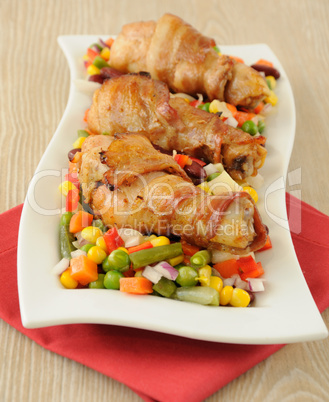 chicken leg wrapped in bacon with vegetables