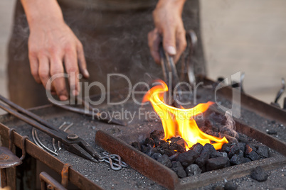 embers, fire, smoke, tools and the hands of a blacksmith
