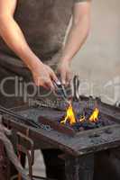 embers, fire, smoke, tools and the hands of a blacksmith